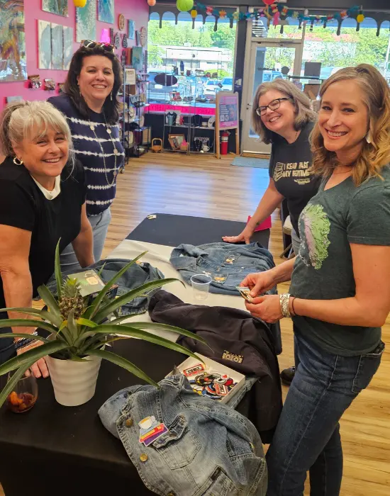 Women collaborating at table with custom patches and denim jackets at Hangout for Art workshop
