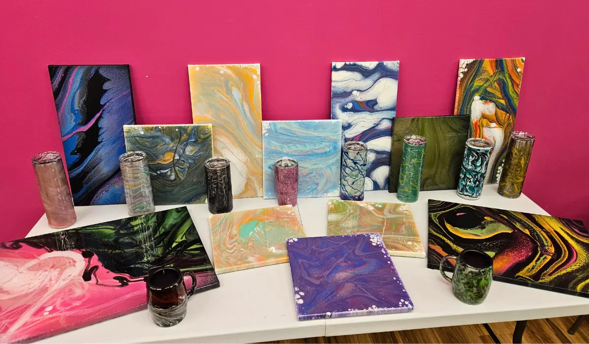 Collection of finished fluid art paintings, resin tumblers, and wine glasses at Hangout for Art