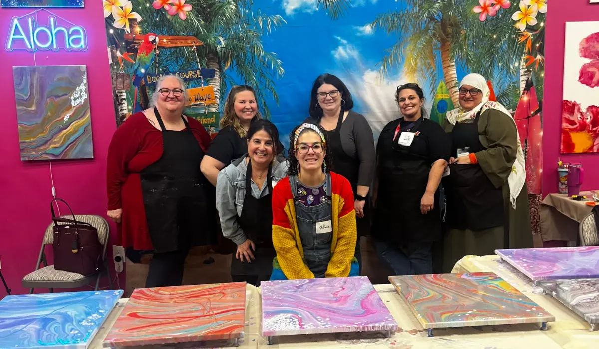 Women's group posing with colorful fluid art creations at Hangout for Art team building event