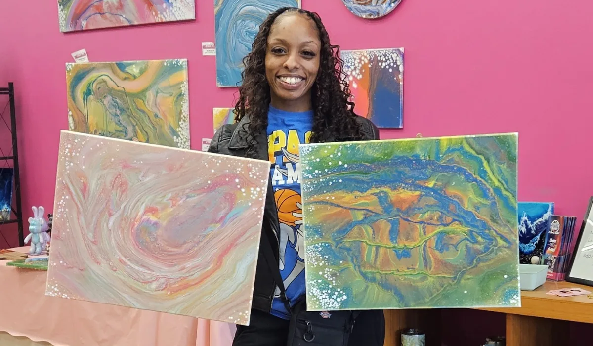 Woman holding two colorful fluid art paintings created during date night at Hangout for Art