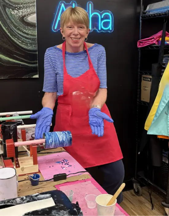 Woman in red apron holding resin art project at Hangout for Art studio in Allentown
